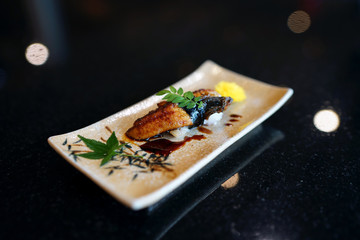 Unagi sushi - A plate of steamed rice topped with grilled freshwater eel and sweet sauce. on wooden table, Traditional Japanese Food.