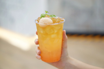 A plastic glass of Iced lychee rose cold brew tea on blurred background, Perfect drink for summer time.