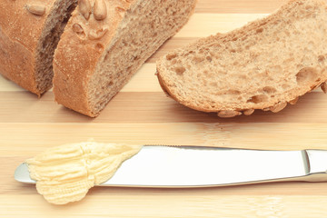 Butter on knife and slice of bread on cutting board