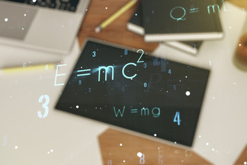 Physical formulas on the background of a table with a digital tablet, papers and laptop, double...
