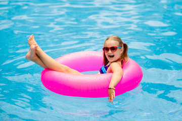 Child in swimming pool on toy ring. Kids swim.