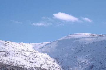 Obraz premium A beautyfool panoramic view of snowy mountain. Dramatic clouds. Trees in the Shed. blue sky. Mt hermon the higher mountain in Israel.