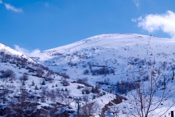A beautyfool panoramic view of snowy mountain. Dramatic clouds. Trees in the Shed. blue sky. Mt hermon the higher mountain in Israel.