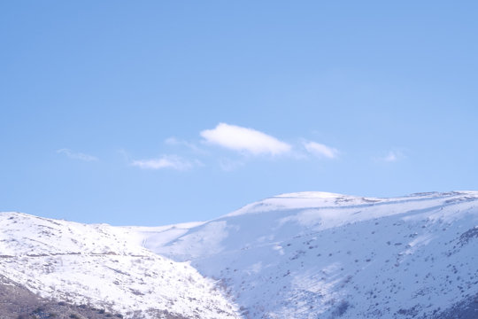 A beautyfool panoramic view of snowy mountain. Dramatic clouds. Trees in the Shed. blue sky. Mt hermon the higher mountain in Israel.