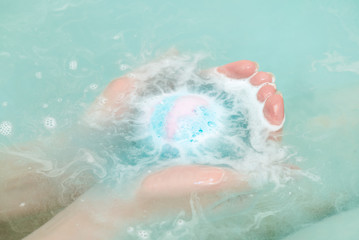 Bath ball in female hands close up in the water.