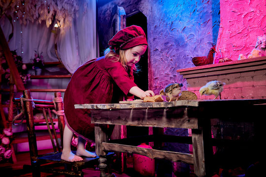 Small girl with little chicken in village interior in the room with wooden table. Easter, holiday and child concept