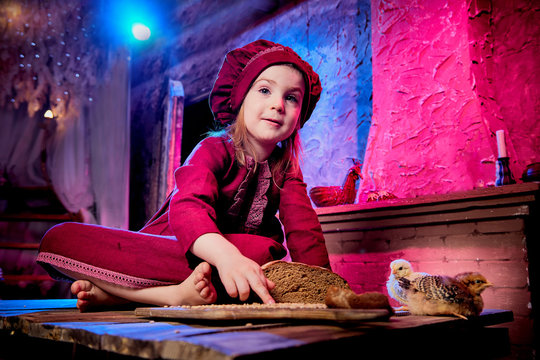 Small girl with little chicken in village interior in the room with wooden table. Easter, holiday and child concept