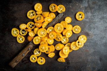 Sliced ripe kumquats on the rustic wooden background. Selective focus. Shallow depth of field.