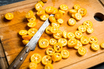Sliced ripe kumquats on the rustic wooden background. Selective focus. Shallow depth of field.