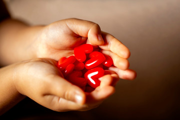 沢山の赤いハートを持つ子供の手