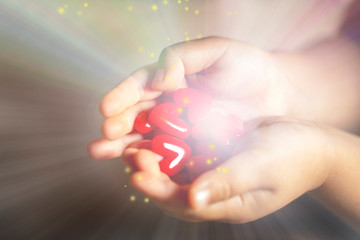 光を放つ沢山の赤いハートのモチーフを持つ子供の手