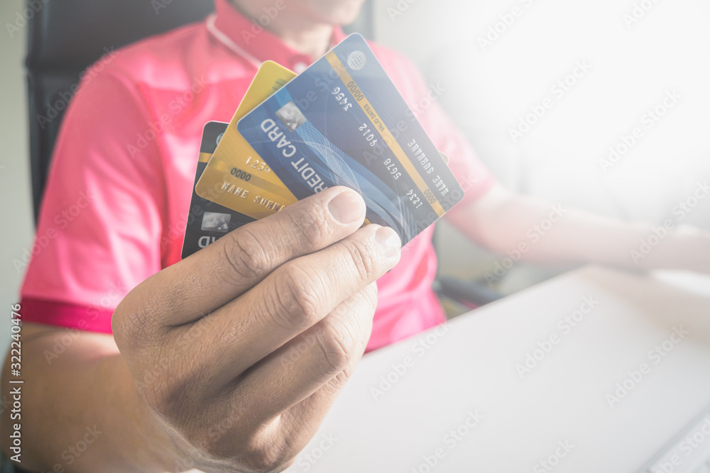 Poster man paying with credit cards on computer at home.