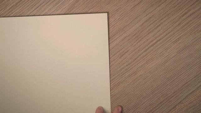 close up of white sheet of paper appearing in shot and girl's hands fold it.