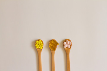 Assorted pharmaceutical medicine. Dosage. Tablets and capsules on a wooden spoon on a white background. Concept of medicine. Alternative homeopathy. Flatley.   copyright of the text.