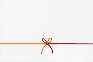Yellow and red ribbon isolated on white background. two colors chamois string tied in a bow.