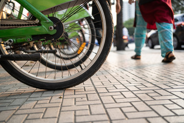 Fototapeta na wymiar Bicycle wheels on footpath with pedestrian walking