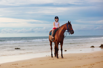 Fototapeta na wymiar Kids riding horse on beach. Children ride horses.
