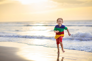 Child playing on ocean beach. Kid at sunset sea.