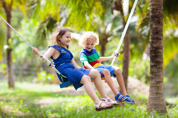 Kids on swing. Playground in tropical resort.