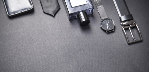Obraz na płótnie Canvas Tie, belt, wristwatch and perfume on the black background. Men accessories