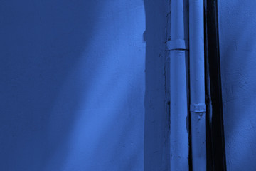 plastered wall blue color with tubes. shadows on the wall