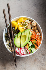 Vegan poke bowl with avocado, tofu, rice, seaweed, carrots and mango, top view. Vegan food concept.