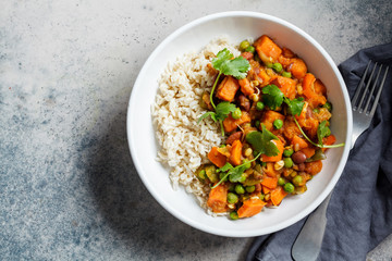 Vegan curry with rice in white bowl, top view. Curry with sweet potato, peas and beans in a plate with rice.