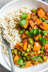 Vegan curry with rice in white bowl, top view. Curry with sweet potato, peas and beans in a plate with rice.