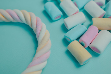 Colorful marshmallow on blue background. Many candies on the table. Twisted marshmallow with candies around.