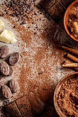 Ingredients for making chocolate background. Cocoa, cocoa butter, sugar, cinnamon and coconut oil on dark background, top view.