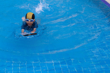 6 years old young boy a swimmer wearing goggle with the dark blue suit and yellow striped black cap...