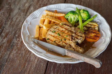 Black pepper pork chop in white plate on wooden table