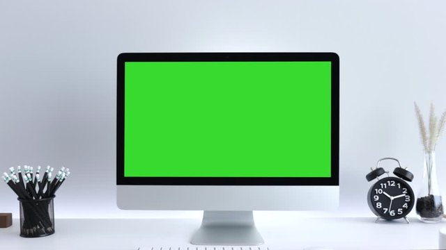 Computer desktop with mock-up green screen white background  in office, Zoom shoulder view.