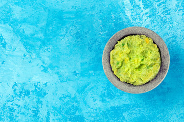 Guacamole in a molcajete, Mexican avocado dip in the traditional stone mortar, shot from above on a...