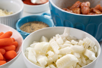White onion on a plate. Close up of fresh organic chopped onion on a plate among some other ingredients on a kitchen table on white background