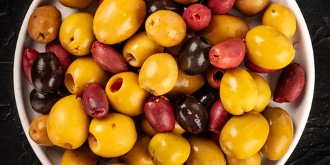 Olives variety close-up panorama. Black, green and red olives, an assortment, shot from above