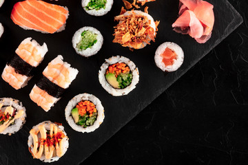 Large sushi set, shot from the top on a black background with a place for text. A flatlay of various maki, nigiri and rolls