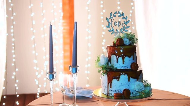 Motion shot wedding cake blue dye and chocolate on top with blue candles, Blurry lights background