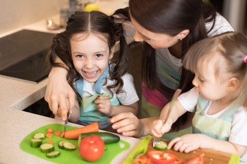 Happy mother and her children enjoy making healthy meal together at their home