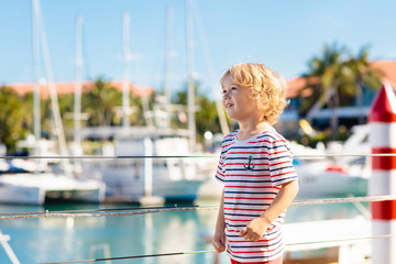 Child watching yacht and boat in harbor. Yachting.