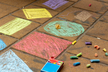 Multi-colored chalk drawings on the pavement tile.
