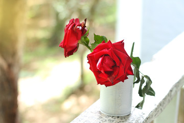 red roses in blue vase, on old wood table background.