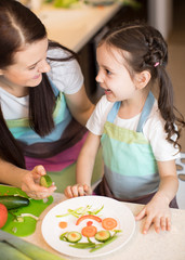Obraz na płótnie Canvas Happy mother and her little daughter enjoy making healthy meal together at their kitchen