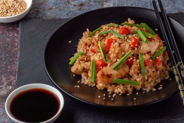 Tori chahan fried Japanese rice with vegetables and chicken in soy sauce in a black plate on a serving board
