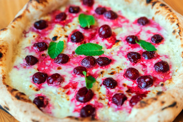 Freshly baked pizza with cherry, mint and cheese close-up