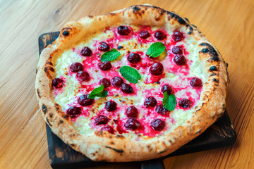 Freshly baked pizza with cheese, sauce, basil and meat on a wooden table
