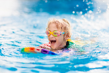 Fototapeta na wymiar Child learning to swim. Kids in swimming pool.