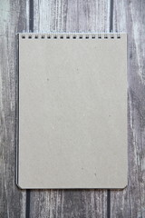 Gray sheet paper from a spiral notebook lies on the background of wooden boards