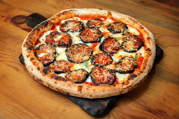 Freshly baked pizza with cheese, sauce and eggplants on a wooden table