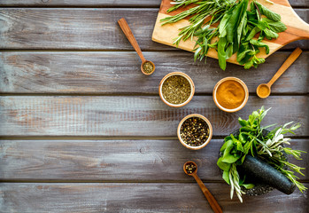 Making spices. Herbs in motar and dry flavorings on dark wooden desk top-down copy space